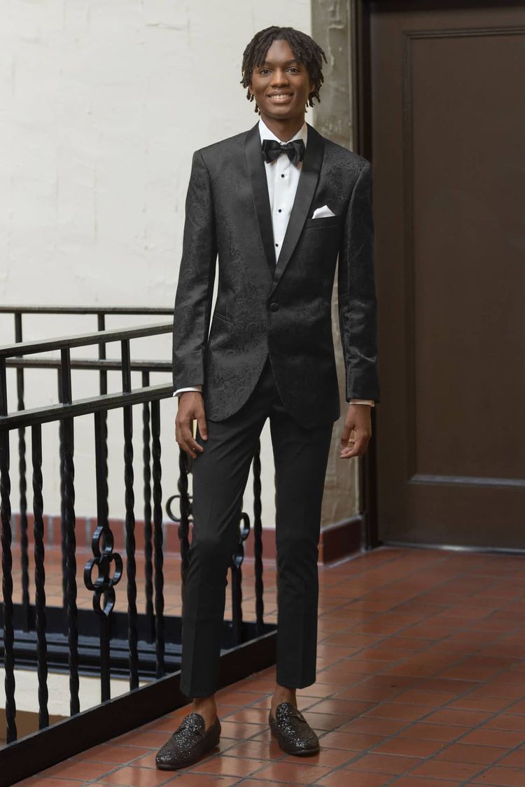 man wearing black paisley jacket with ultra slim stretch trousers and a black bow tie
